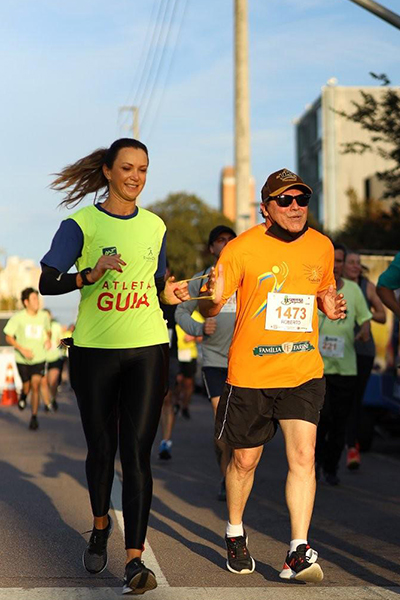 Guia voluntária da Radar DV corre com atleta com deficiência visual durante prova de rua, em uma cena marcada por alegria, autonomia e inclusão.